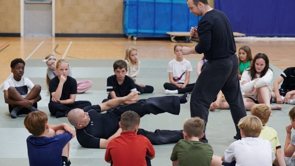 Image of self defence instructors demonstrating to children how to defend themselves when they are on the floor.
